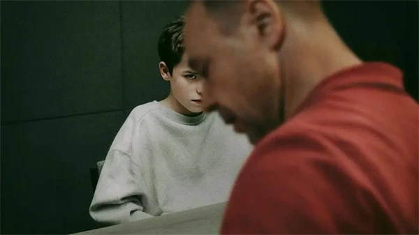 A man and a boy sit at a table in a tense scene from "Adolescence".
