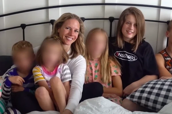 A woman smiles with children on a bed in Devil in the Family: The Fall of Ruby Franke.